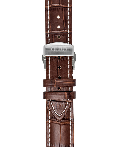 Gros plan sur le bracelet Grand Tourisme en cuir marron embossé crocodile à surpiqûres blanches et sa boucle déployante en acier brossé gravée OURO.