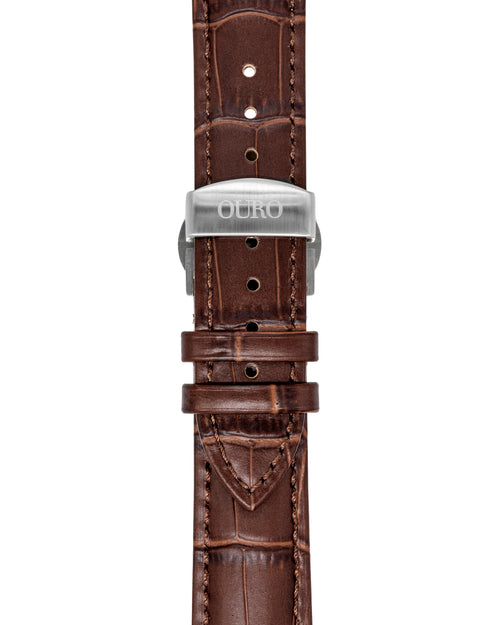 Gros plan sur le bracelet Grand Tourisme en cuir marron embossé crocodile à surpiqûres marrons et sa boucle déployante en acier brossé gravée OURO.