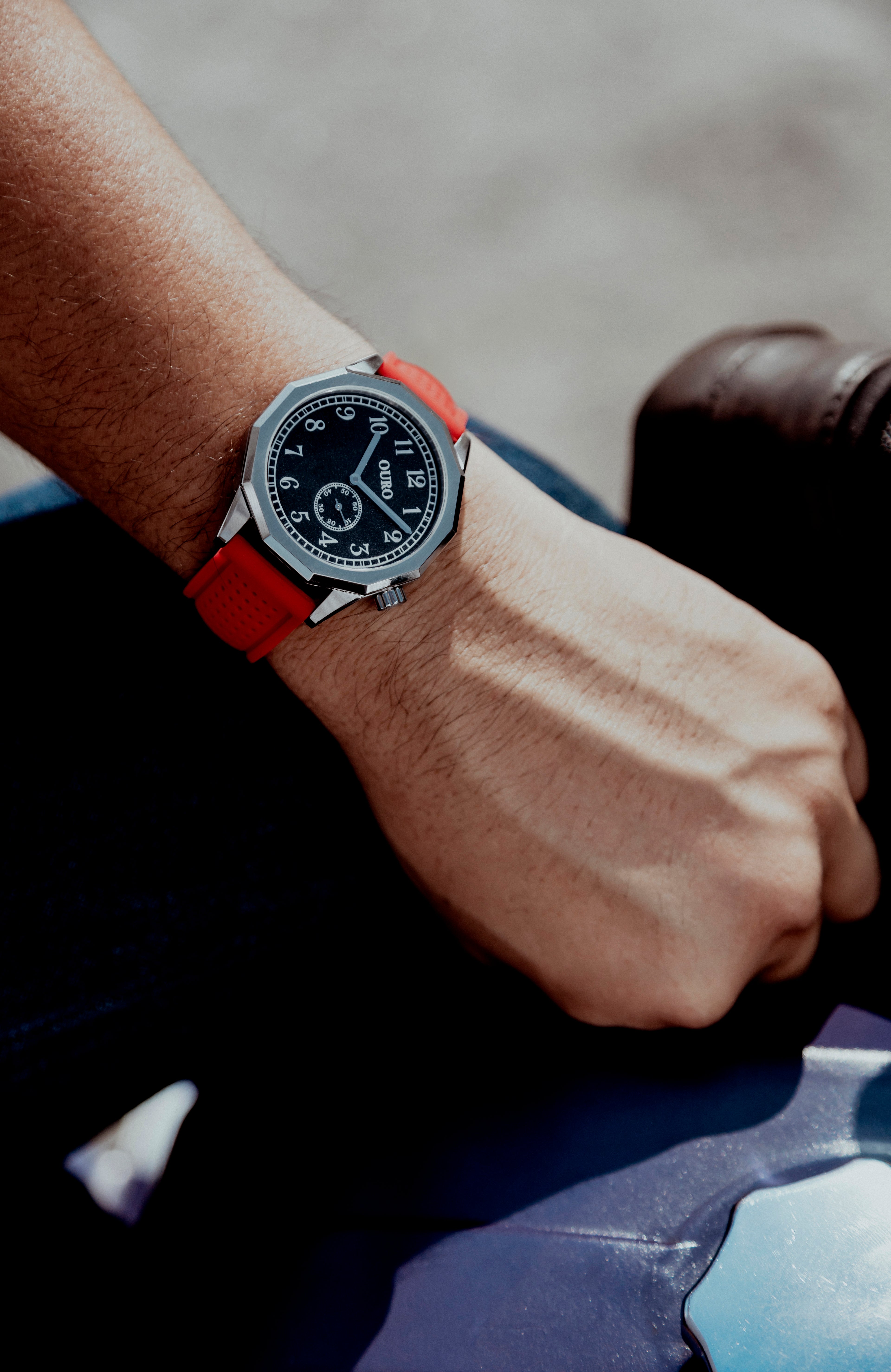 Montre OURO RW-001 associée au bracelet Sport en silicone rouge portée au poignet par un motard prés de sa machine.
