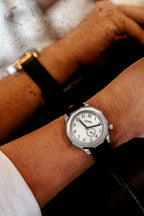 Montre OURO RW-002 avec bracelet en cuir noir portée au poignet, se reflétant dans un miroir dans un cadre vintage et élégant.