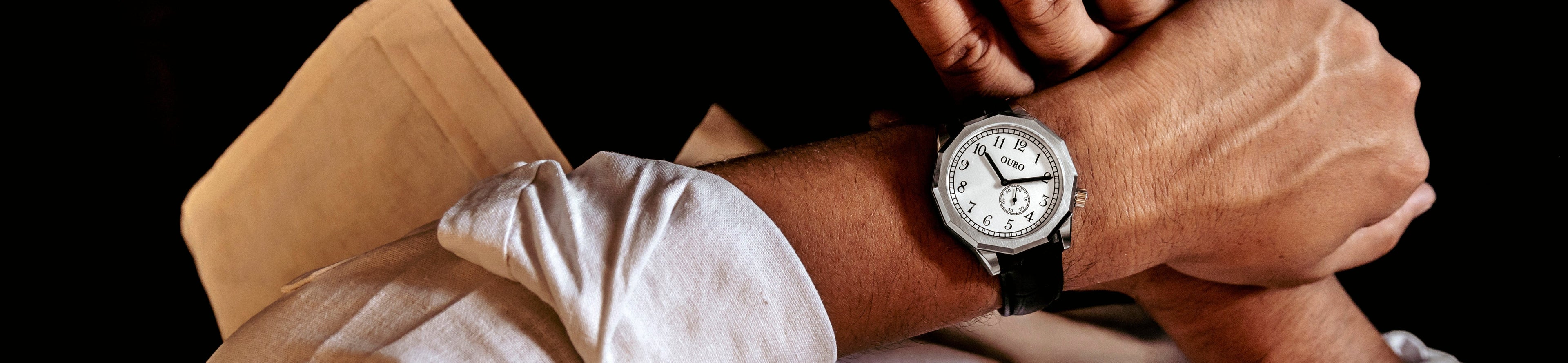 Driver’s watch RW-002 à cadran inox brossé, portée au poignet avec une chemise blanche dans un environnement sombre.